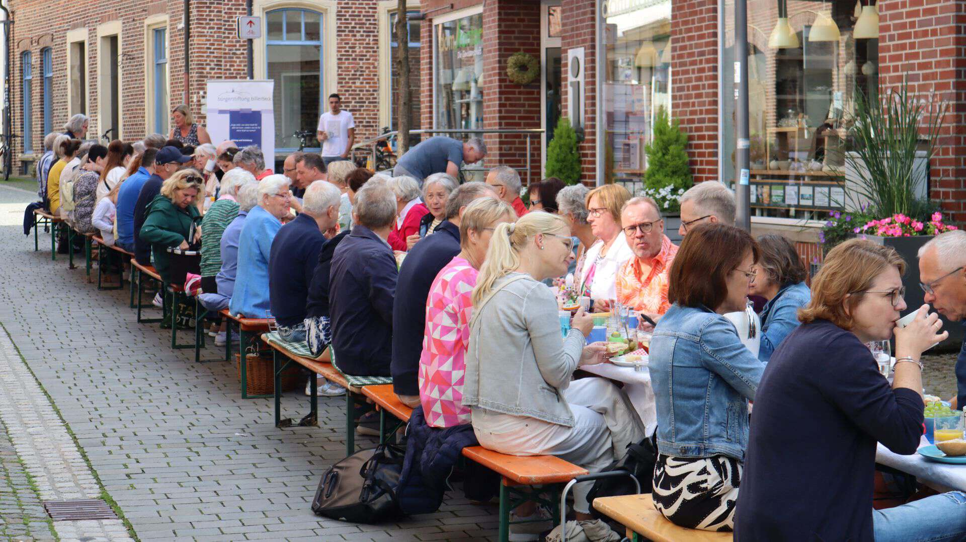 Viele Menschen sitzen an einer langen Tafel in der Fußgängerzone in Billerbeck