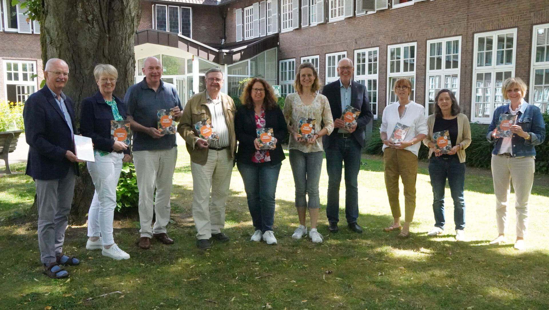 Eine gemischte Gruppe von Personen präsentiert das Jubiläumsbuch der Tafel Coesfeld
